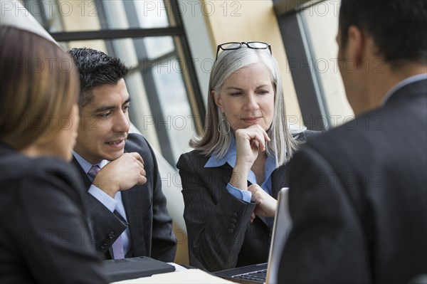 Business people using laptop in meeting