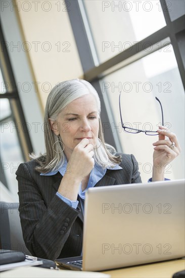 Pensive Caucasian businesswoman using laptop