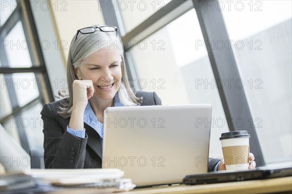 Smiling Caucasian businesswoman using laptop