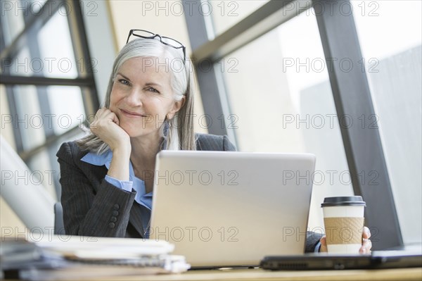 Portrait of smiling Caucasian businesswoman using laptop