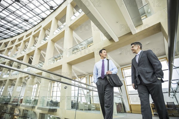 Smiling businessmen talking and walking in lobby