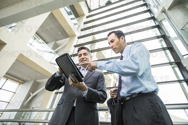 Businessmen using digital tablet in lobby