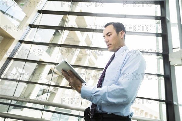 Serious Mixed Race businessmen using digital tablet in lobby