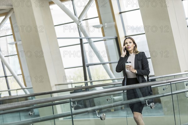 Mixed Race businesswoman talking on cell phone in lobby