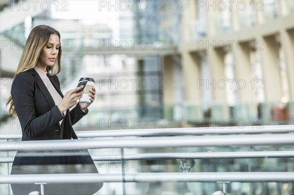 Mixed Race businesswoman texting on cell phone in lobby