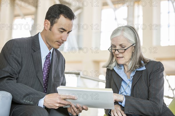 Business people reading paperwork in lobby
