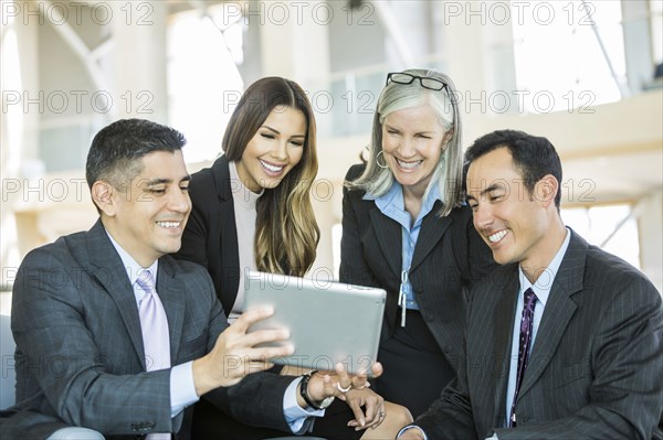 Smiling business people reading digital tablet in lobby