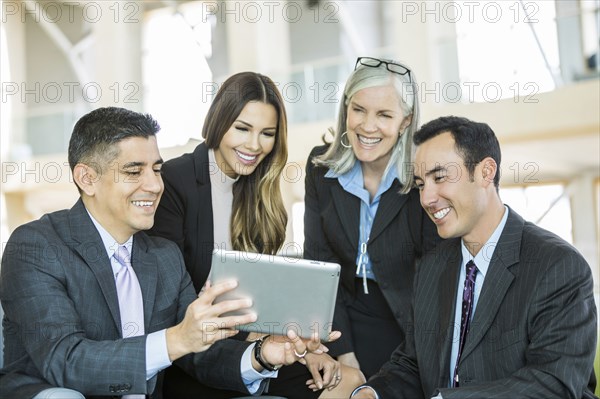 Smiling business people reading digital tablet in lobby