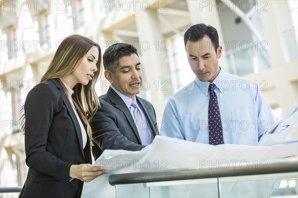 Serious business people reading blueprint in lobby