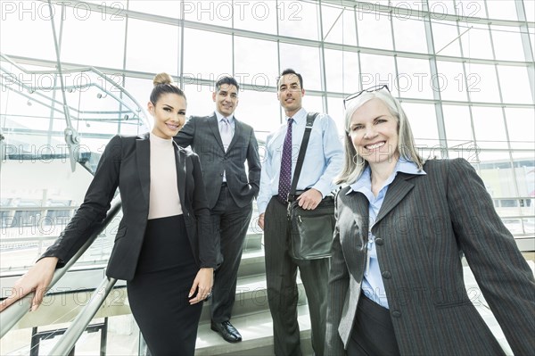 Portrait of smiling business people standing on staircase