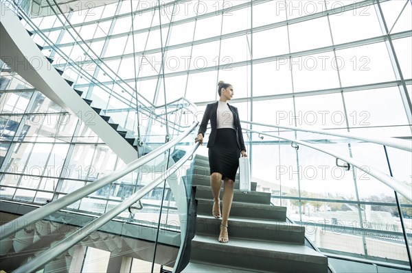 Pensive Mixed Race businesswoman descending staircase