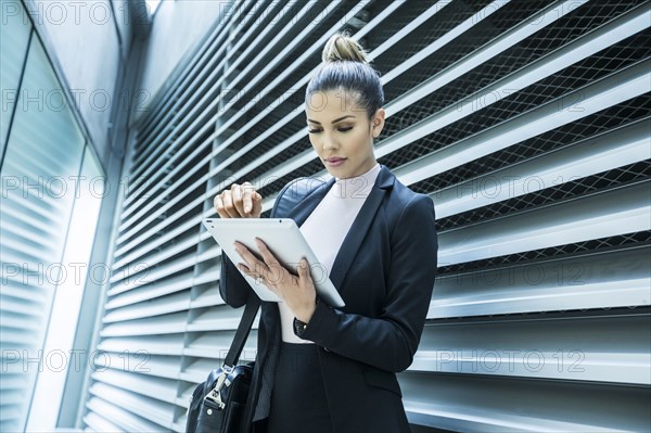 Serious Mixed Race businesswoman using digital tablet in corridor