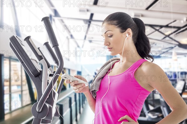 Caucasian woman listening to cell phone in gymnasium