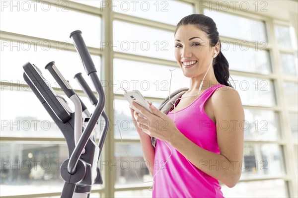 Caucasian woman listening to cell phone in gymnasium