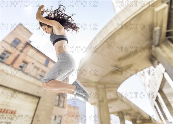 Caucasian woman jumping in city