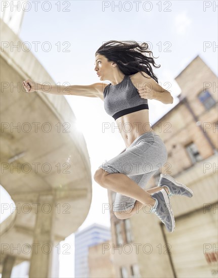 Caucasian woman jumping and punching in city