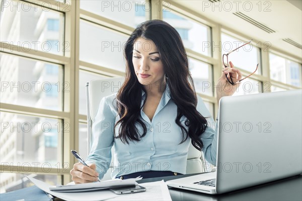 Caucasian businesswoman writing on paperwork