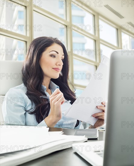 Caucasian businesswoman reading paperwork