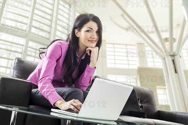 Caucasian businesswoman using laptop in lobby