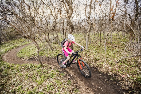 Caucasian girl riding bicycle on forest path