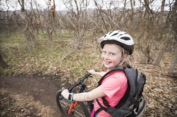 Caucasian girl riding bicycle on forest path