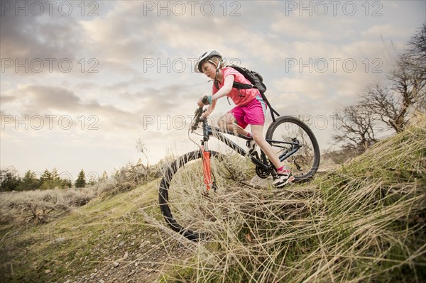 Caucasian girl riding bicycle on hill