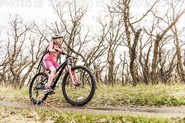 Caucasian girl riding bicycle on forest path