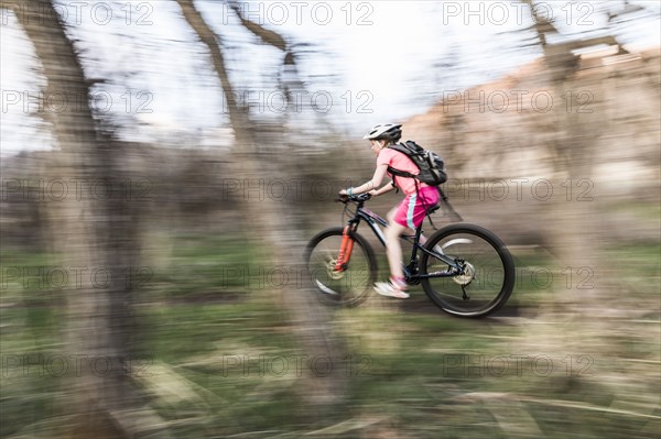 Caucasian girl riding bicycle on forest path