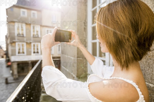 Caucasian woman photographing with cell phone in city