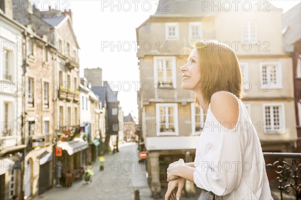 Caucasian woman leaning on balcony in city