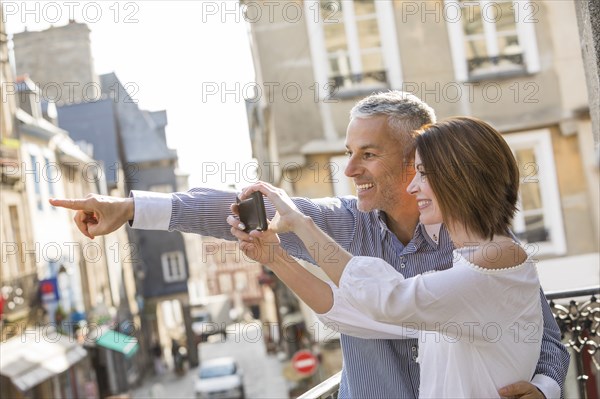 Caucasian couple photographing with cell phone in city