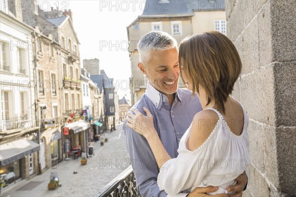 Caucasian couple hogging on balcony in city