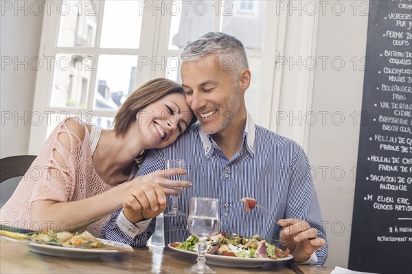 Caucasian couple cuddling in restaurant