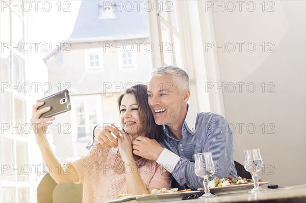 Caucasian couple posing for cell phones selfie in restaurants