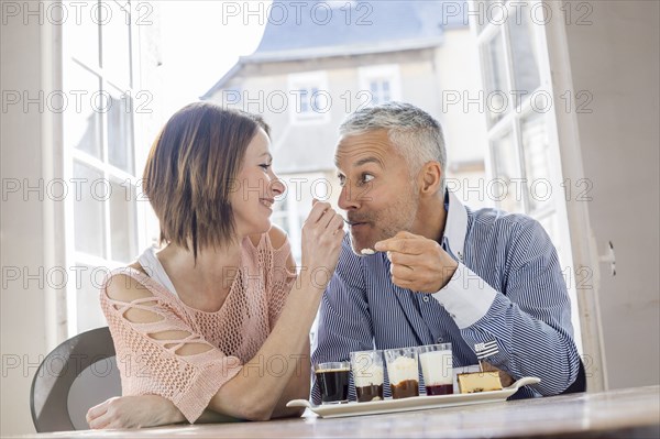 Caucasian woman feeding man dessert in restaurant