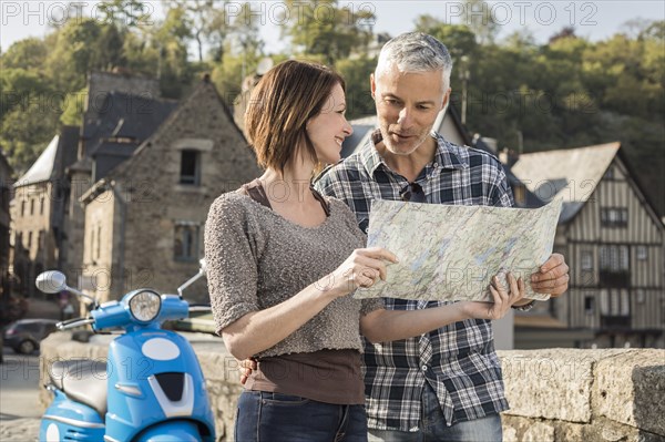 Caucasian couple near blue motor scooter reading map