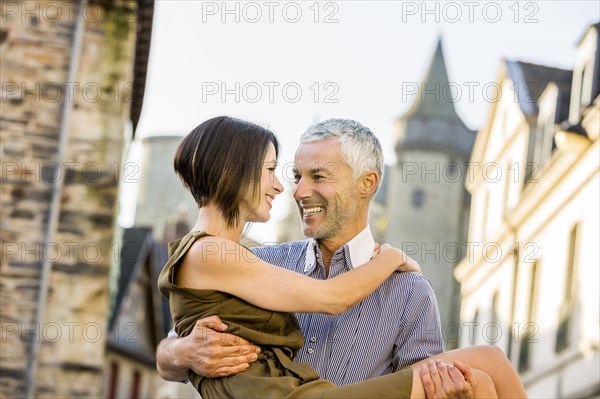 Caucasian man carrying a woman in city