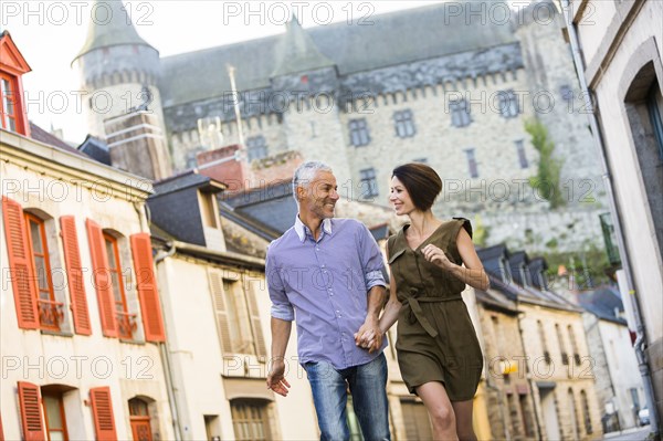 Caucasian couple holding hands walking in city