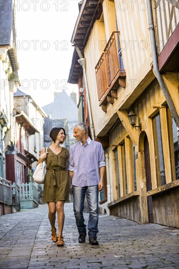 Caucasian couple holding hands walking in city