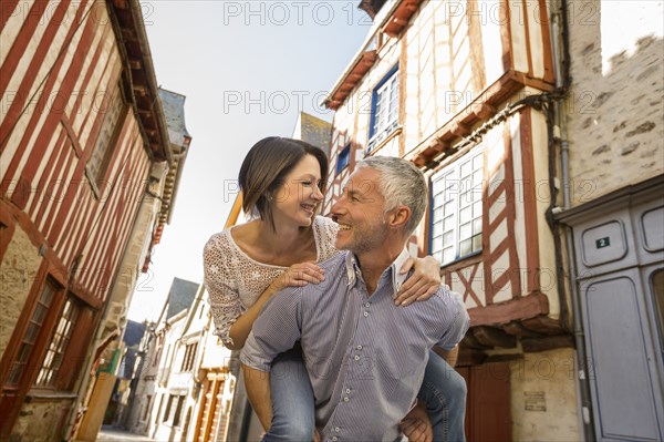 Caucasian man caring woman piggyback in city