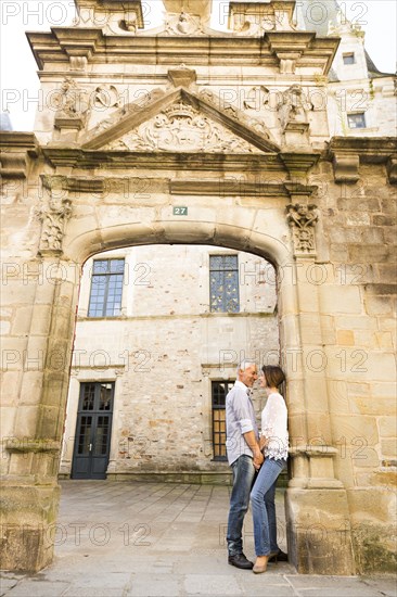 Caucasian couple leaning in arch