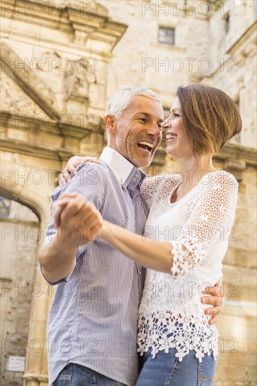 Caucasian couple dancing near building