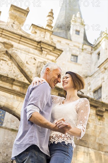 Caucasian couple dancing near building