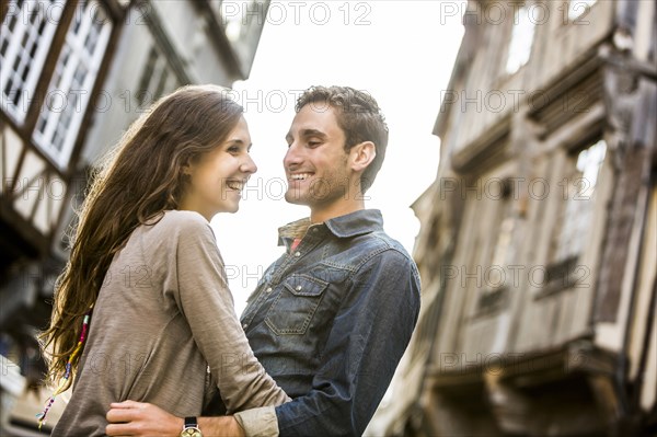 Caucasian couple hugging in city