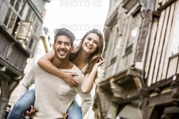 Man carrying woman piggyback in city