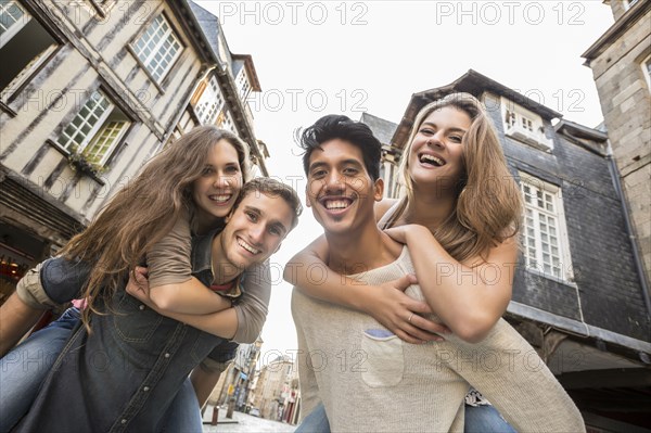 Men carrying women piggyback in city