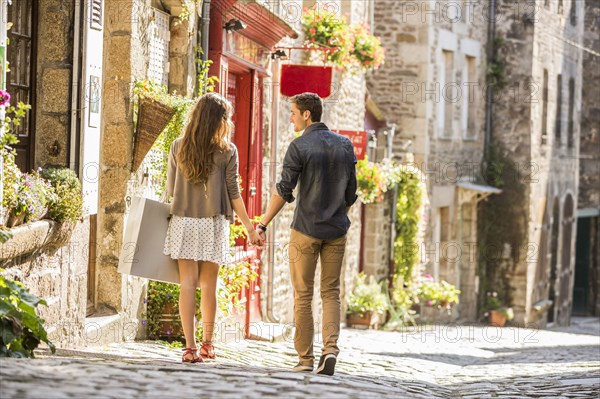 Caucasian couple holding hands walking in city