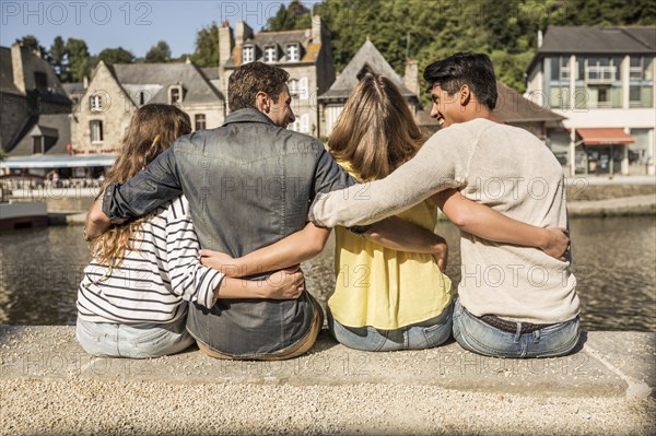 Friends sitting and hugging at waterfront