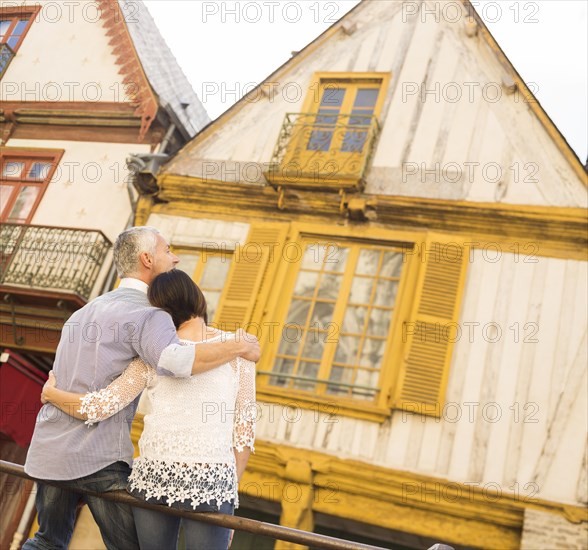 Caucasian couple sitting on railing in city