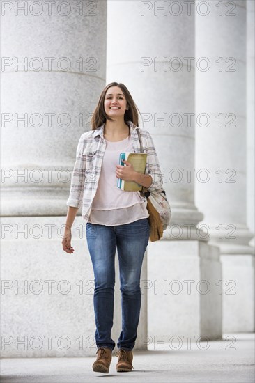 Caucasian woman carrying books and backpack at school